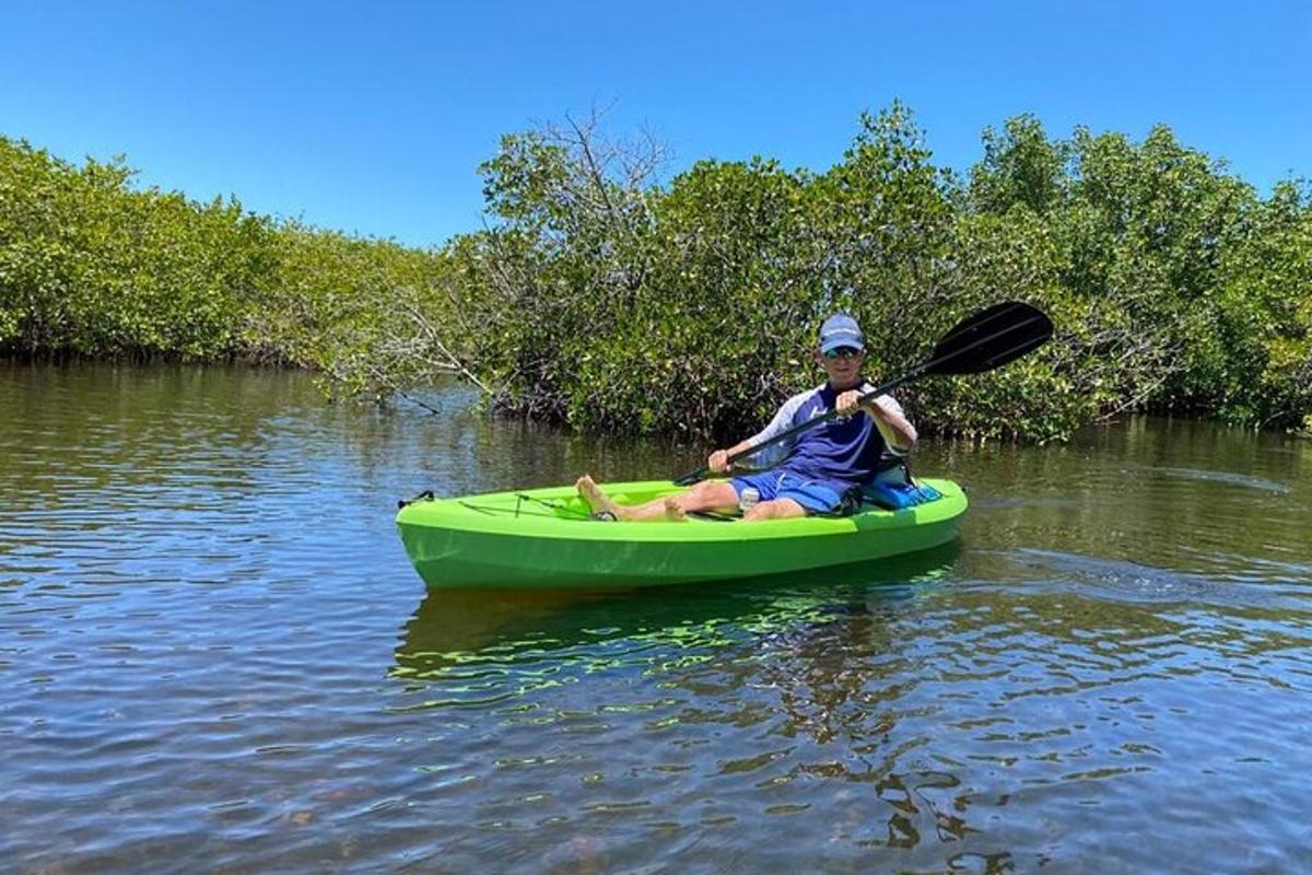 một người đàn ông đang ngồi trên chiếc thuyền kayak màu xanh lá cây trên mặt nước