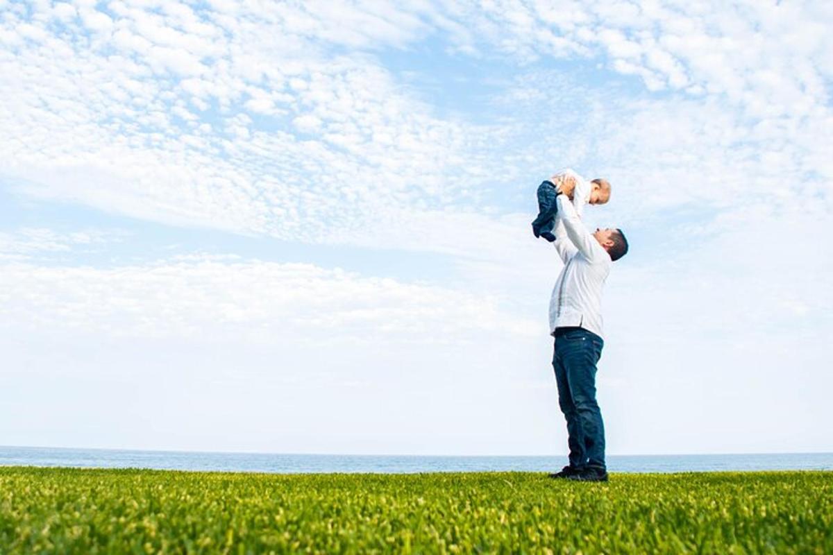a man holding a baby in a field