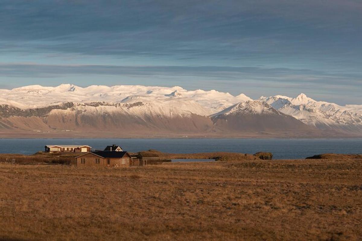 una casa en medio de un campo con montañas cubiertas de nieve