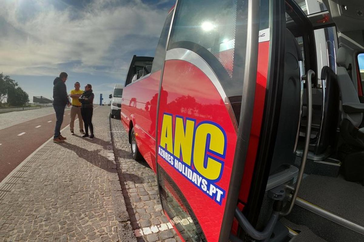 skupina lidí stojící vedle červeného autobusu