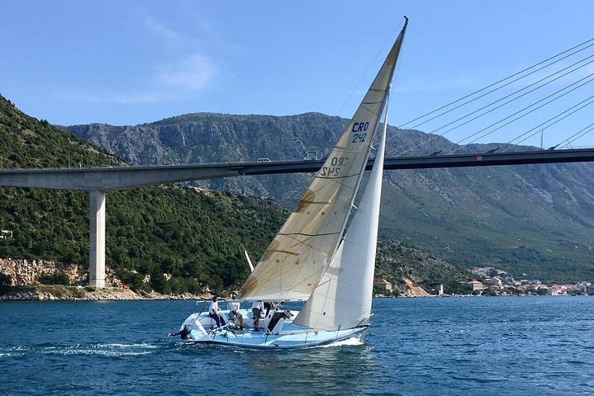 egy vitorlás a vízben egy híd alatt