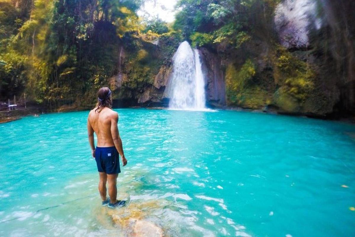 un home dret a l'aigua davant d'una cascada