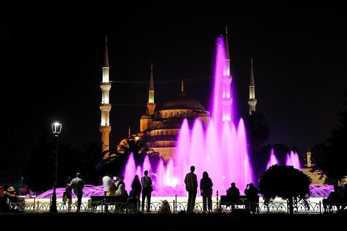 mor ışıklı bir binanın önündeki çeşme