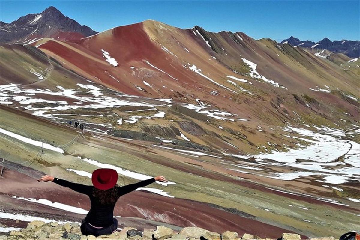 una persona seduta su una roccia che guarda una montagna