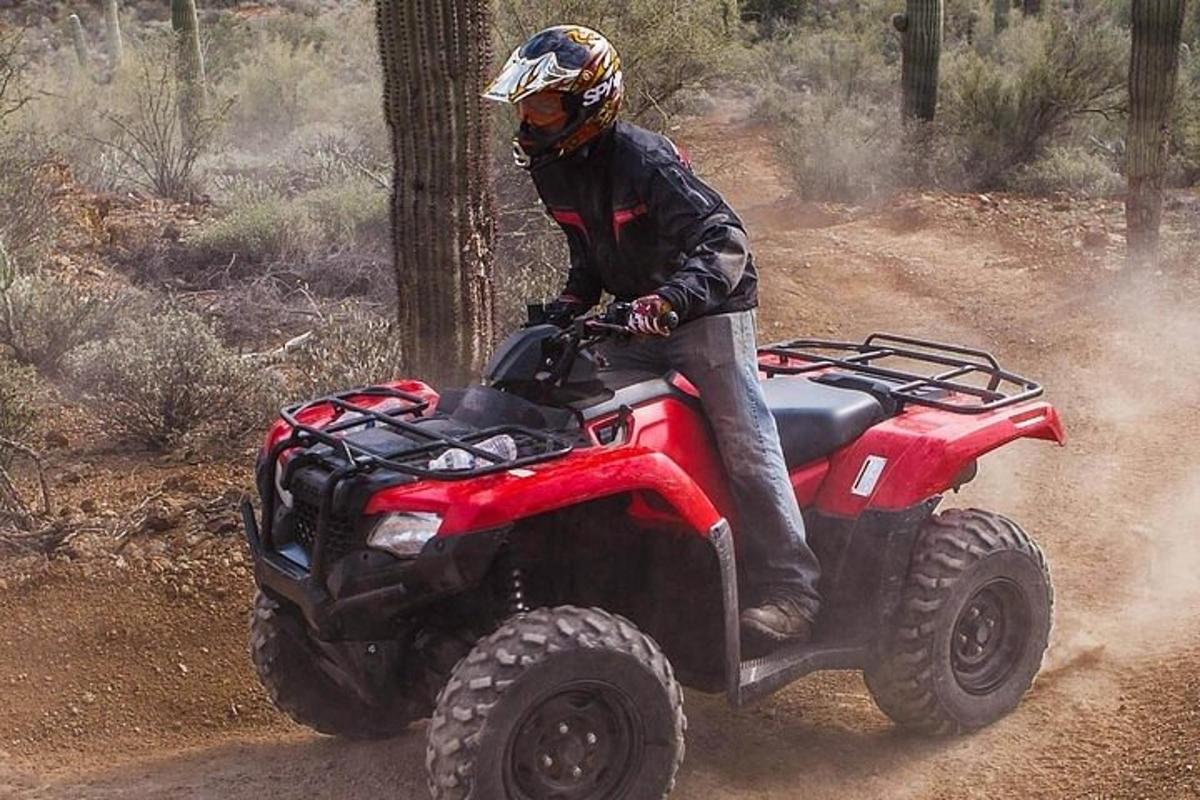 Un hombre que viaja en un vehículo de cuatro ruedas por un sendero