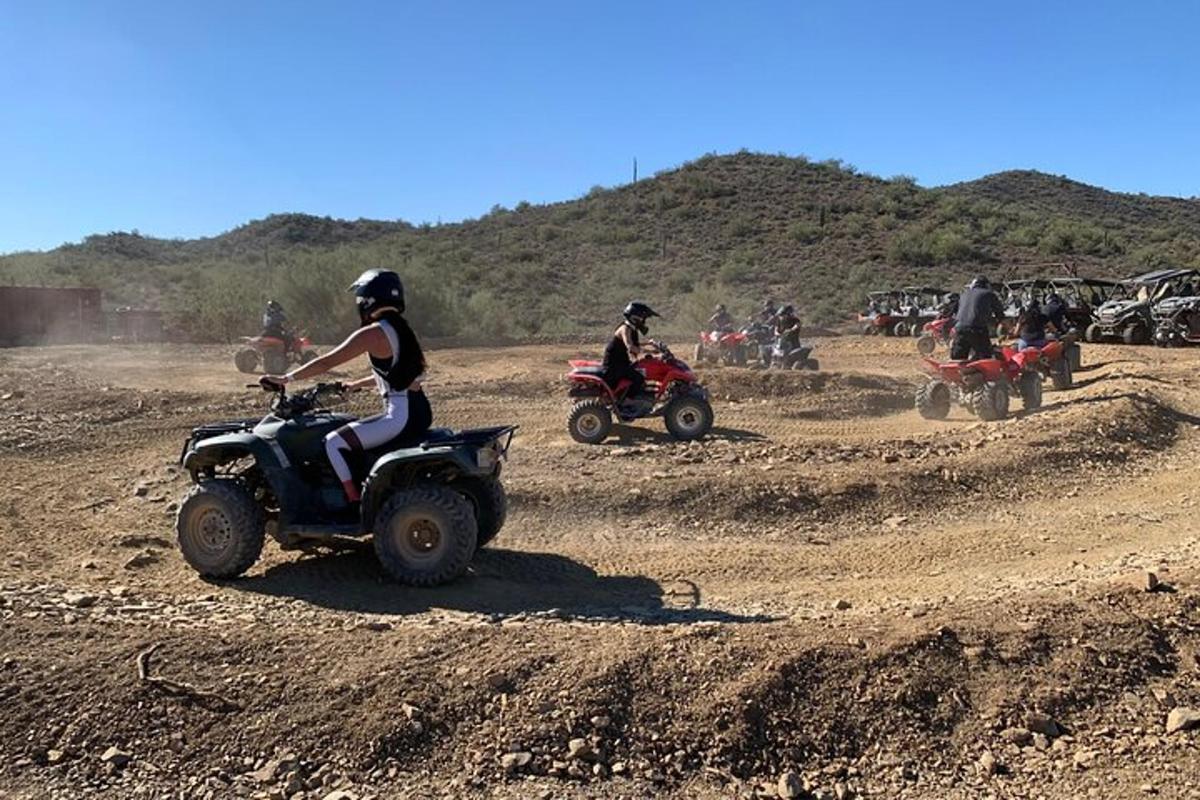 Un grupo de personas viajando en vehículos todo terreno en un campo de tierra.