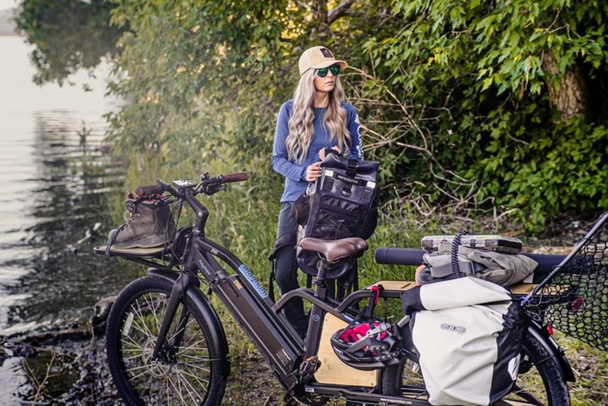 una donna in piedi accanto a una bicicletta vicino all'acqua