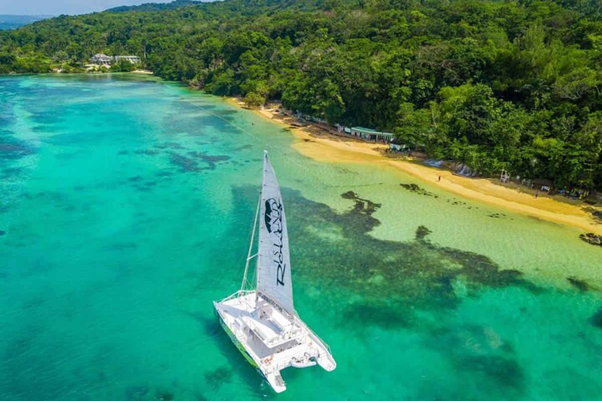 a sail boat in the water near a beach