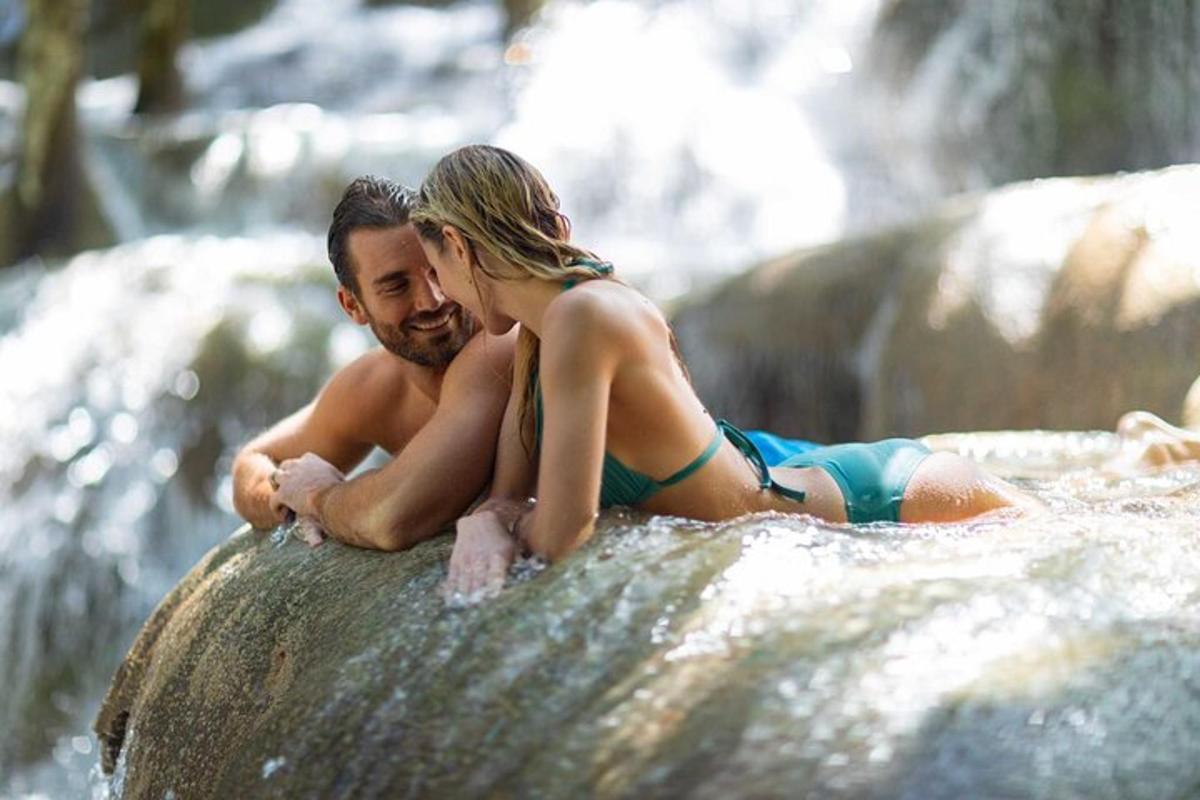 Un hombre y una mujer en traje de baño sentados en una cascada