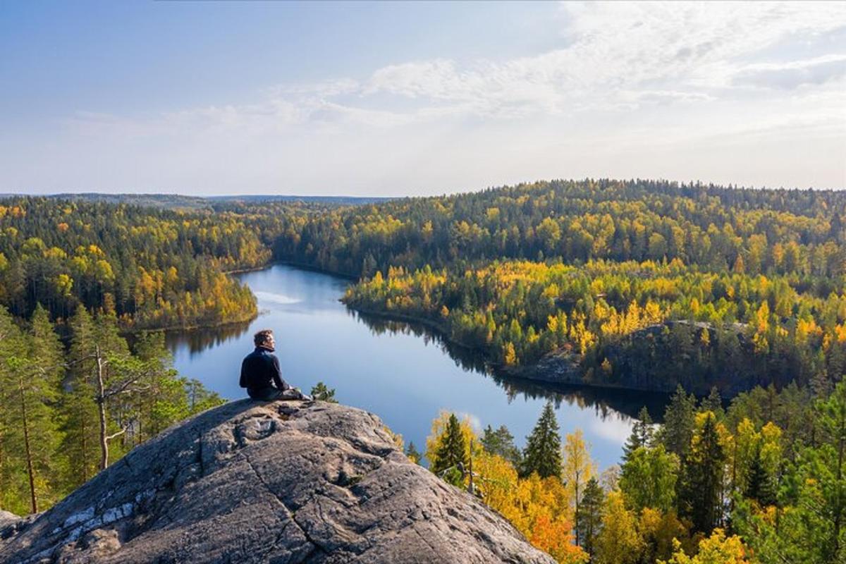 muž sedící na vrcholu skály s výhledem na jezero