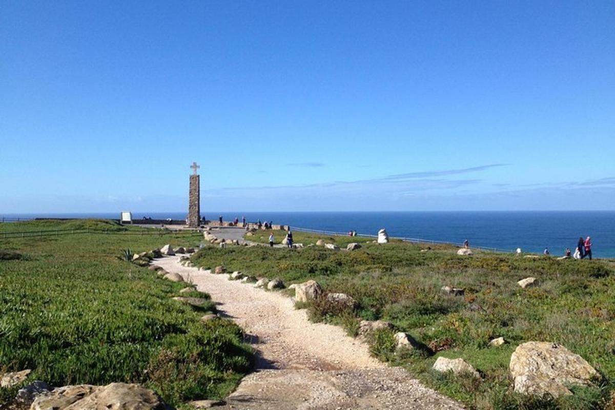 Un camino que conduce a un faro en un campo con el océano.