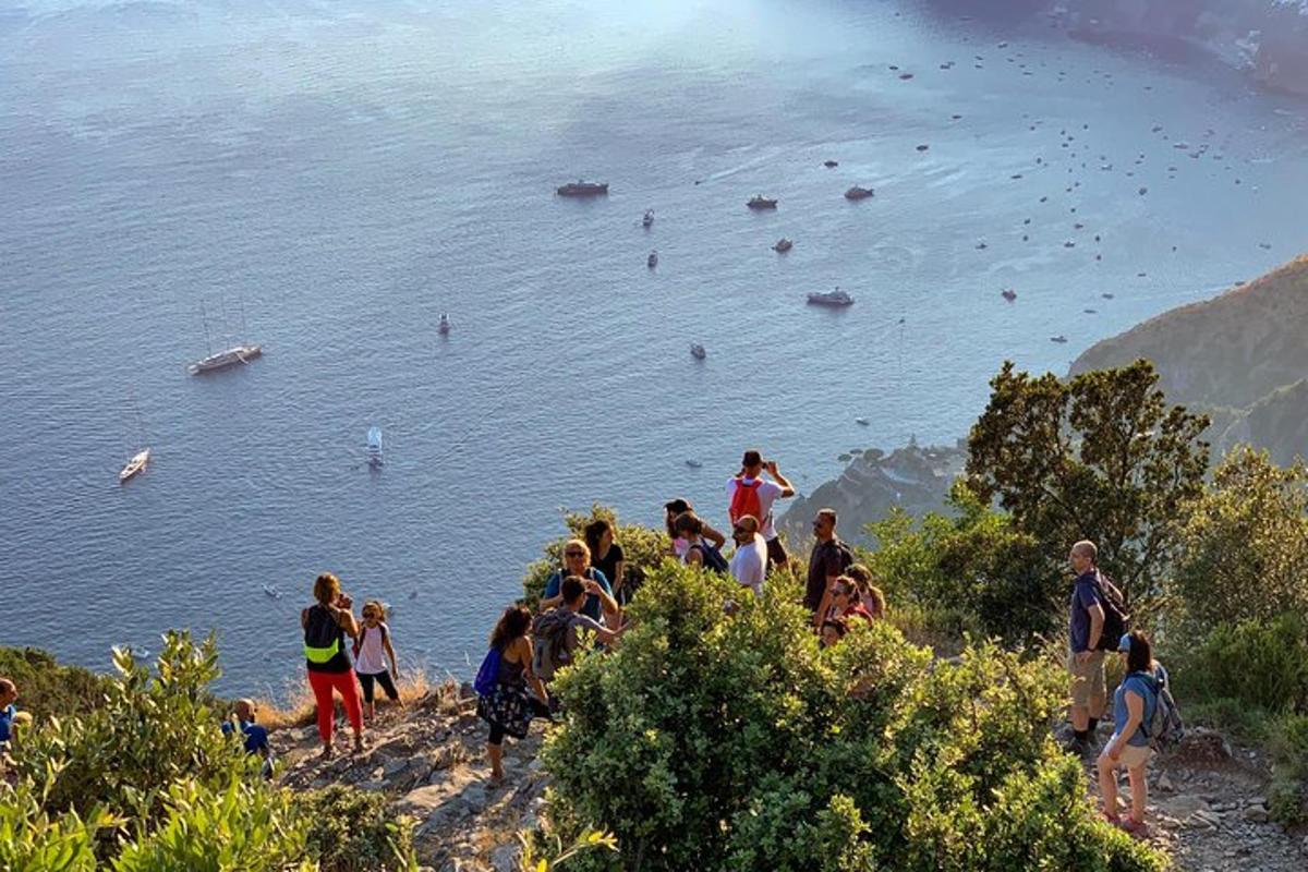 um grupo de pessoas em pé em uma colina perto da água