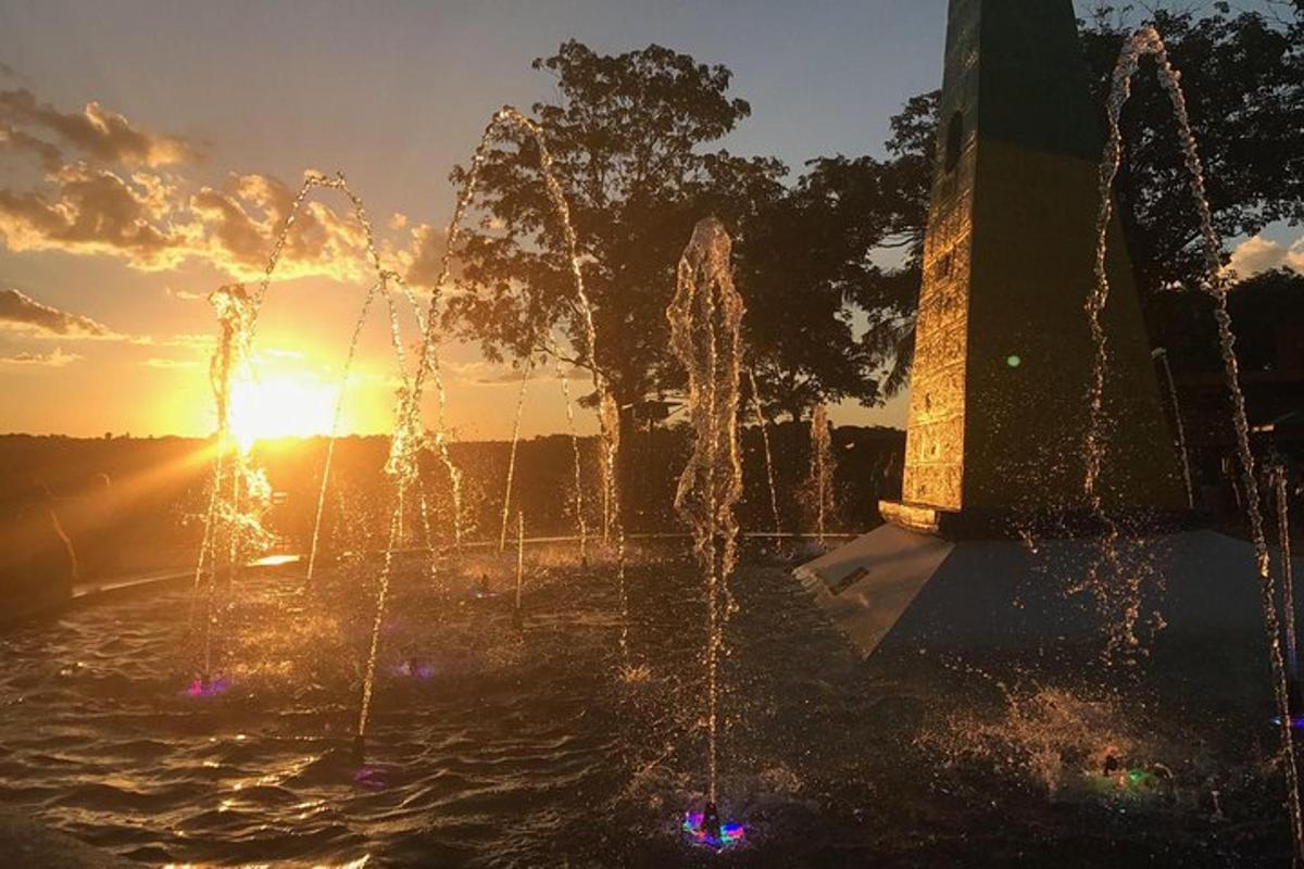 a water fountain with the sun setting in the background