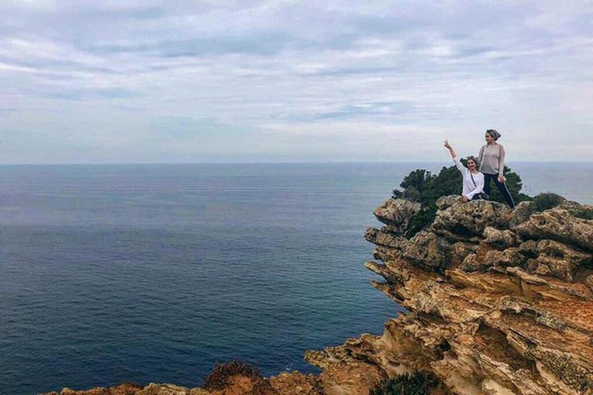 dva lidé stojící na vrcholu útesu s výhledem na oceán