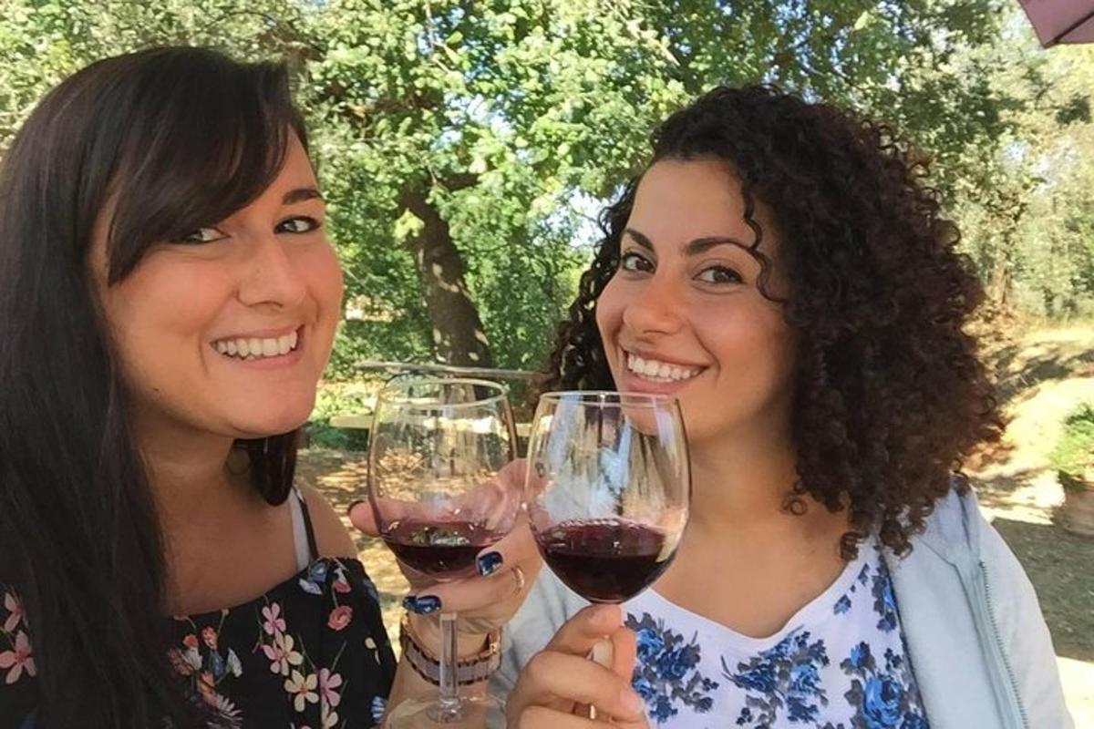 divas sievietes tur rokās sarkanvīna glāzes