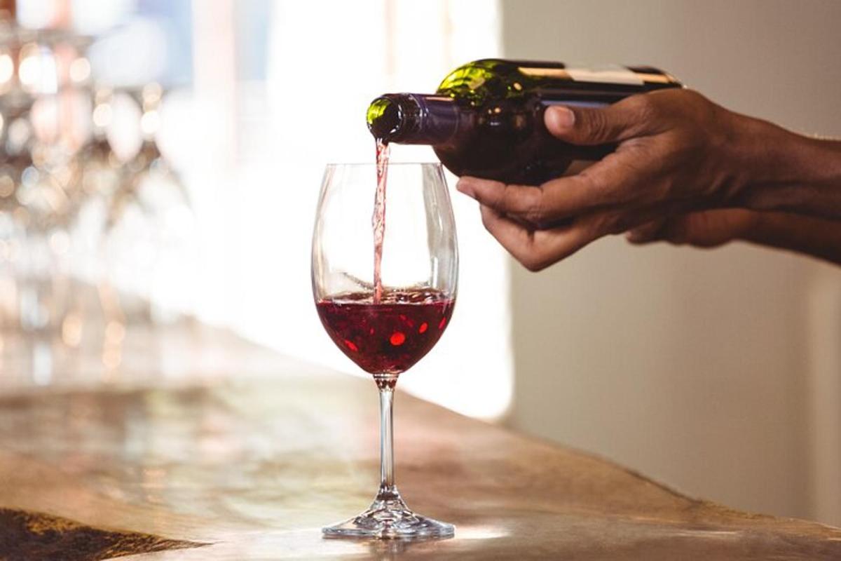 una persona che versa vino rosso in un bicchiere da vino