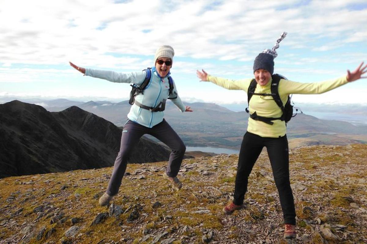 dos personas saltando en la cima de una montaña