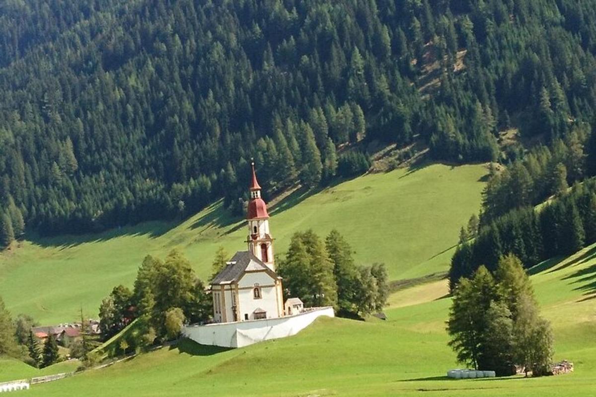 una iglesia en la cima de una colina verde con árboles