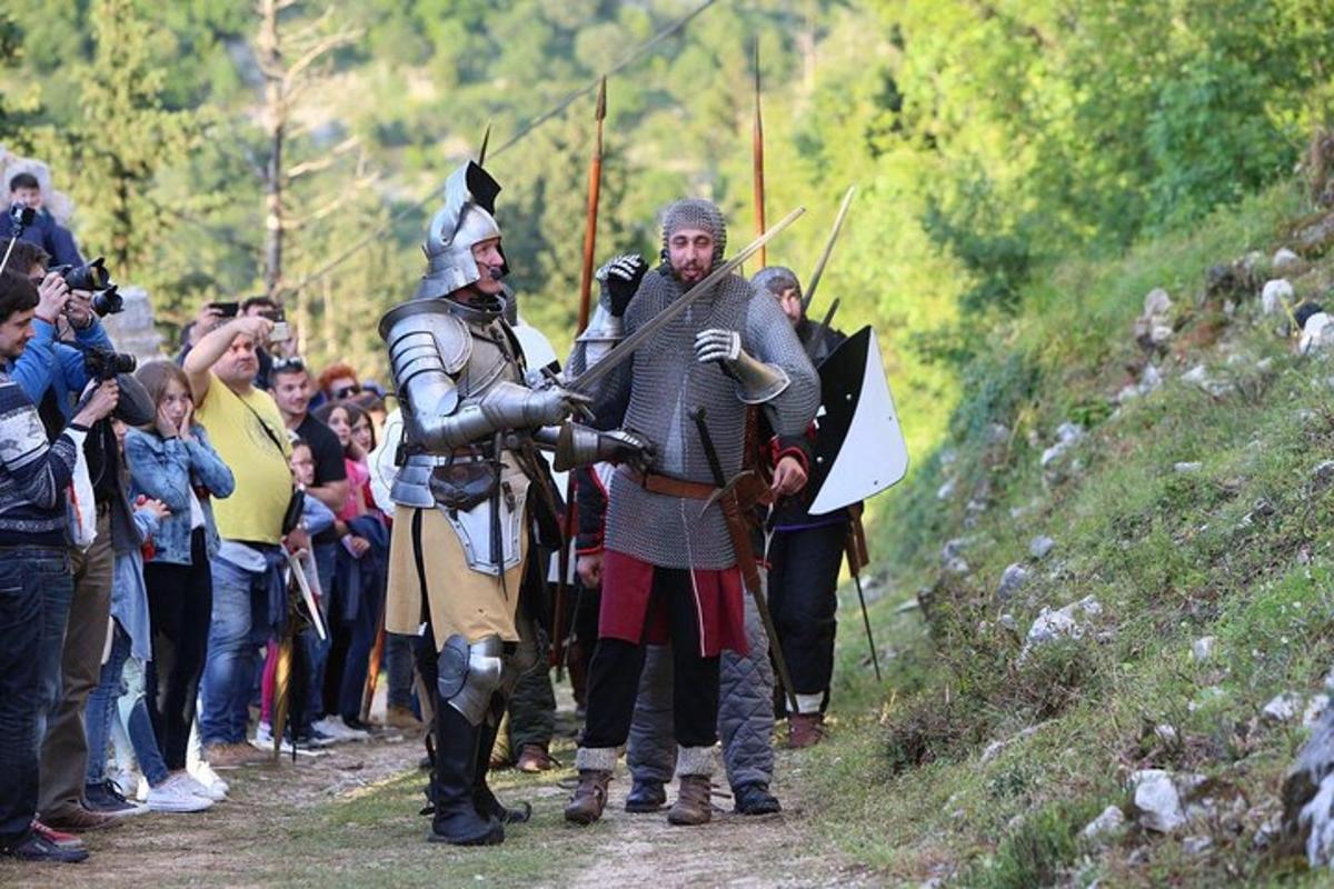 μια ομάδα ανθρώπων που στέκονται σε έναν χωματόδρομο με πανοπλία