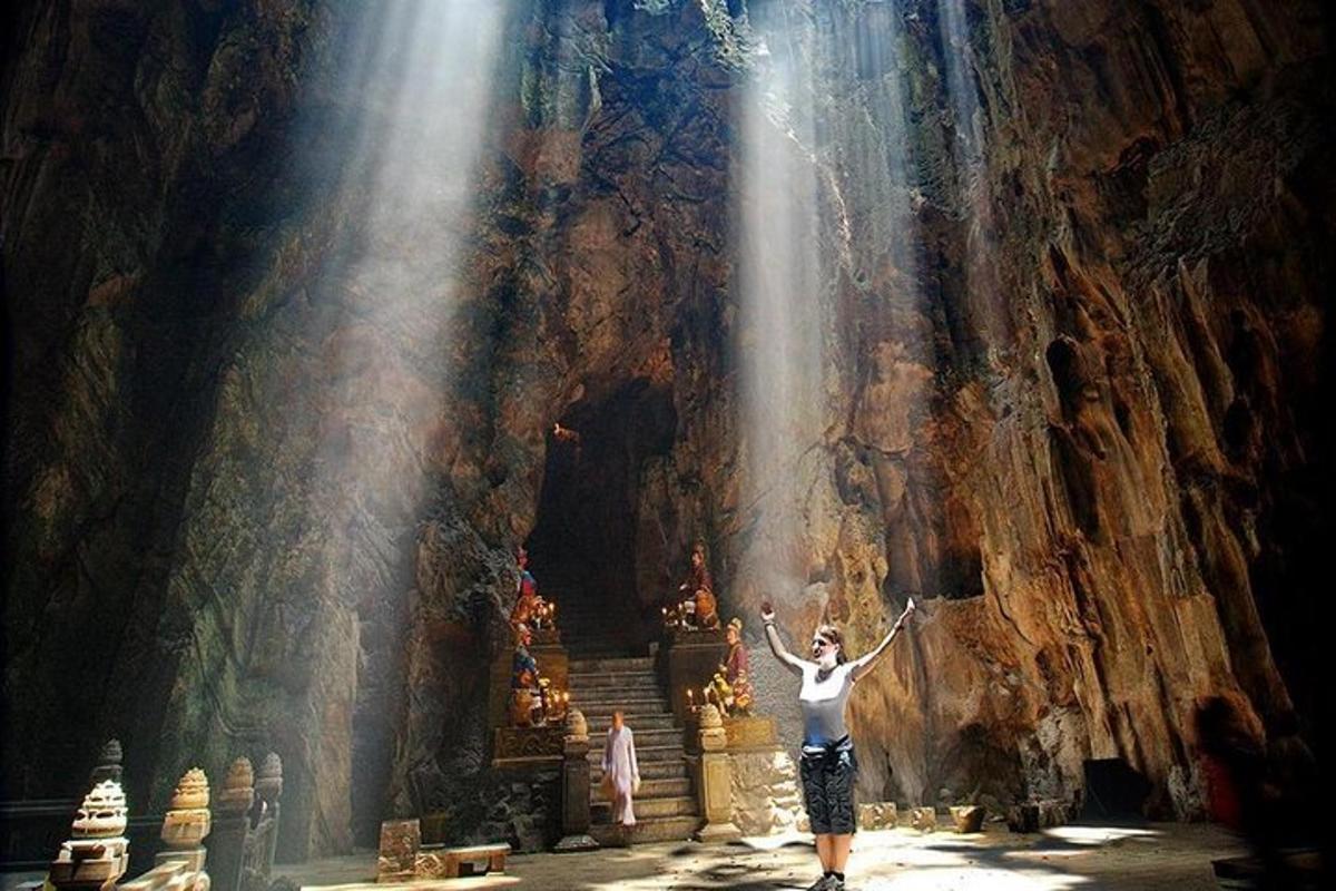 seorang wanita berdiri di hadapan air terjun di dalam sebuah gua