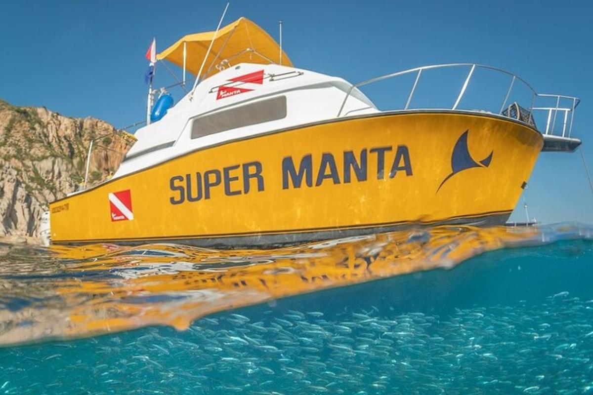a yellow boat in the water next to a cliff