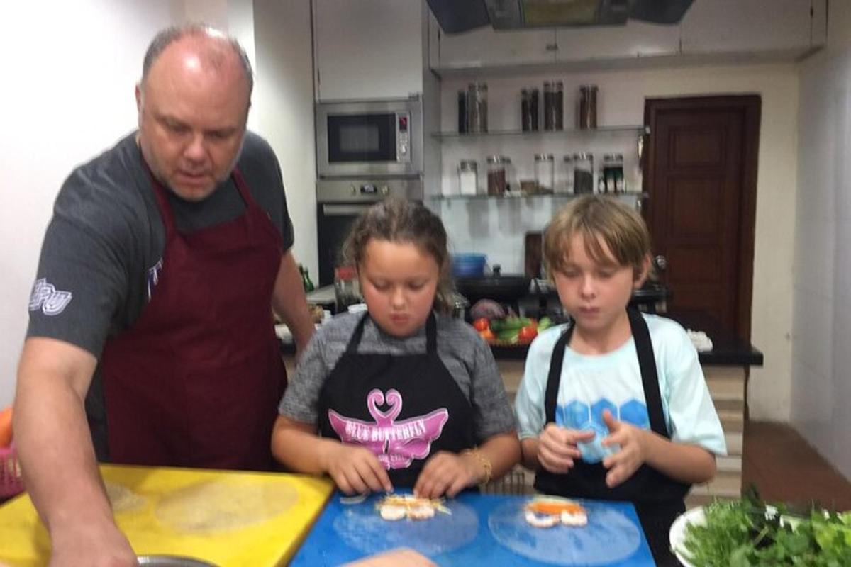 a man and two children in a kitchen making food
