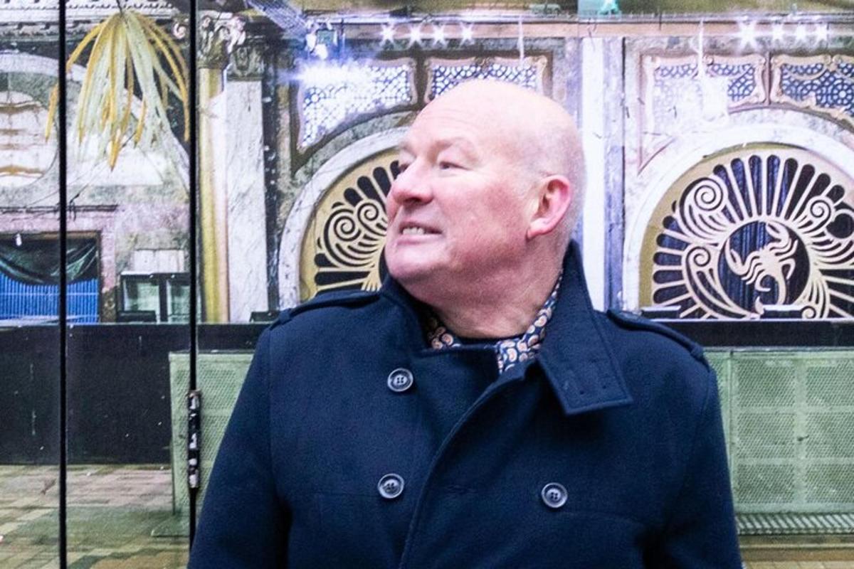 ein älterer Mann steht vor einem Gebäude