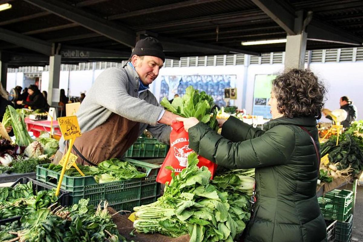 Un hombre y una mujer comprando verduras en un mercado.