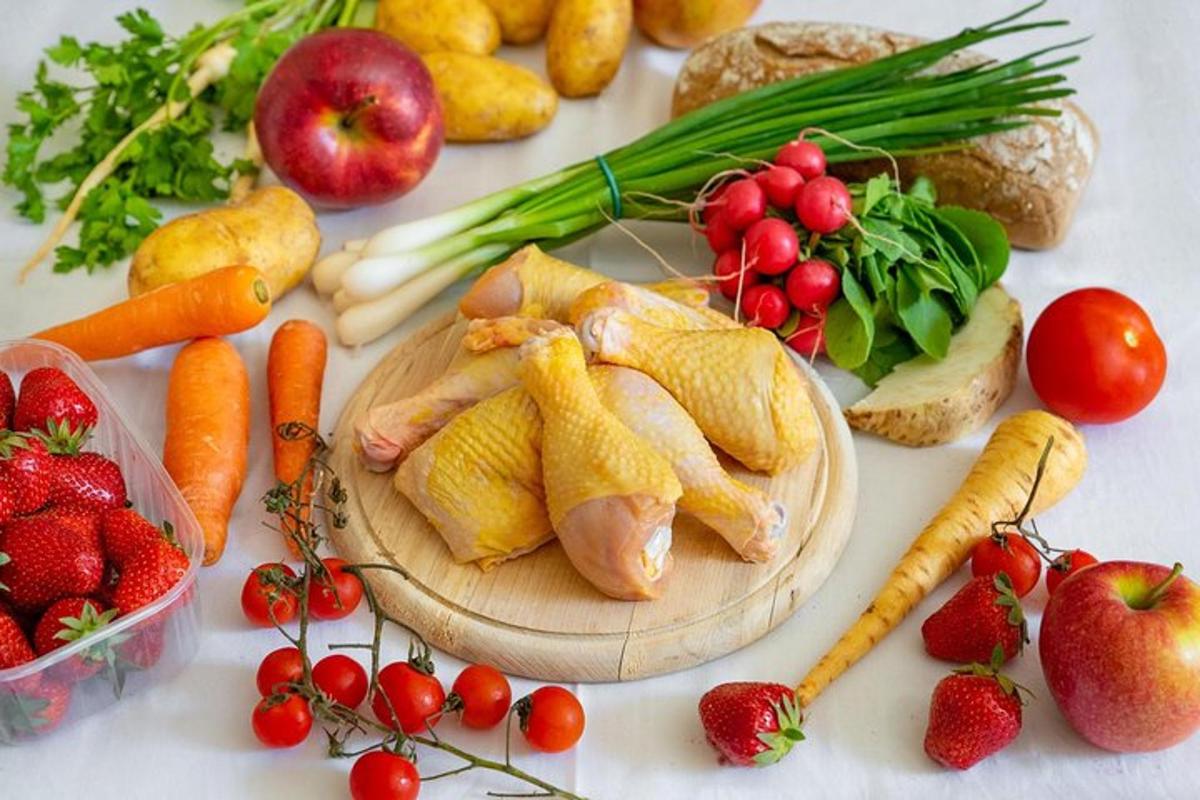 a table topped with fruits and vegetables with chickens on a cutting board