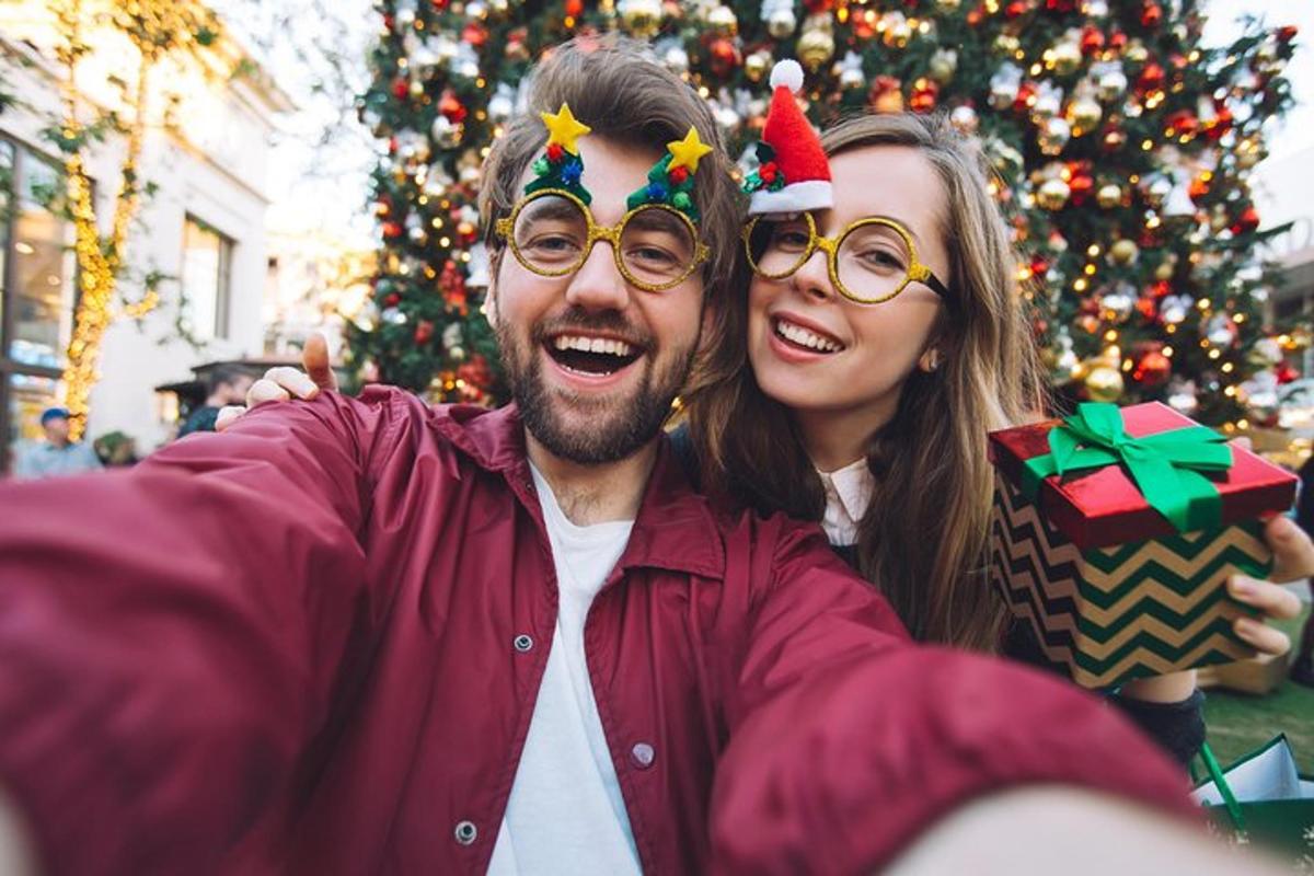 Un hombre y una mujer de pie junto a un árbol de Navidad.