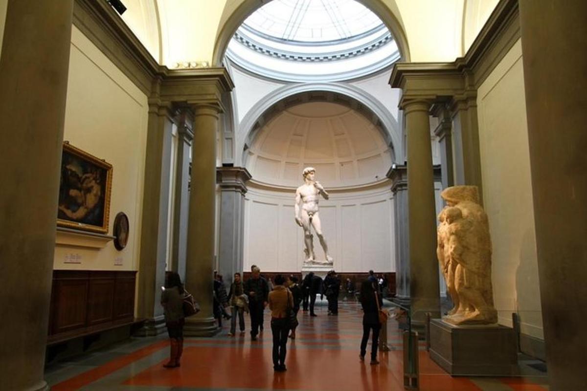 Un grupo de personas paseando por un museo con una estatua.