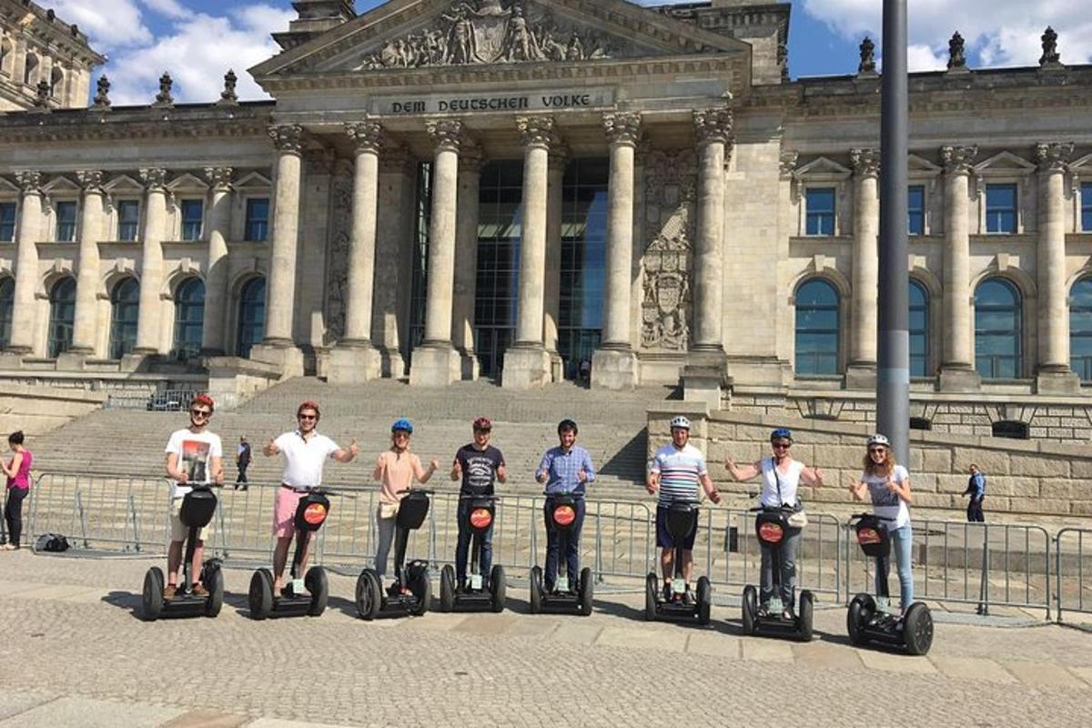um grupo de pessoas andando de segway em frente a um prédio