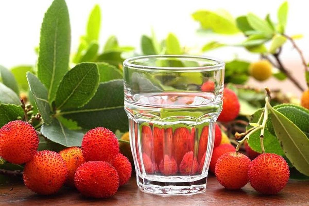 a glass of water next to a bunch of strawberries