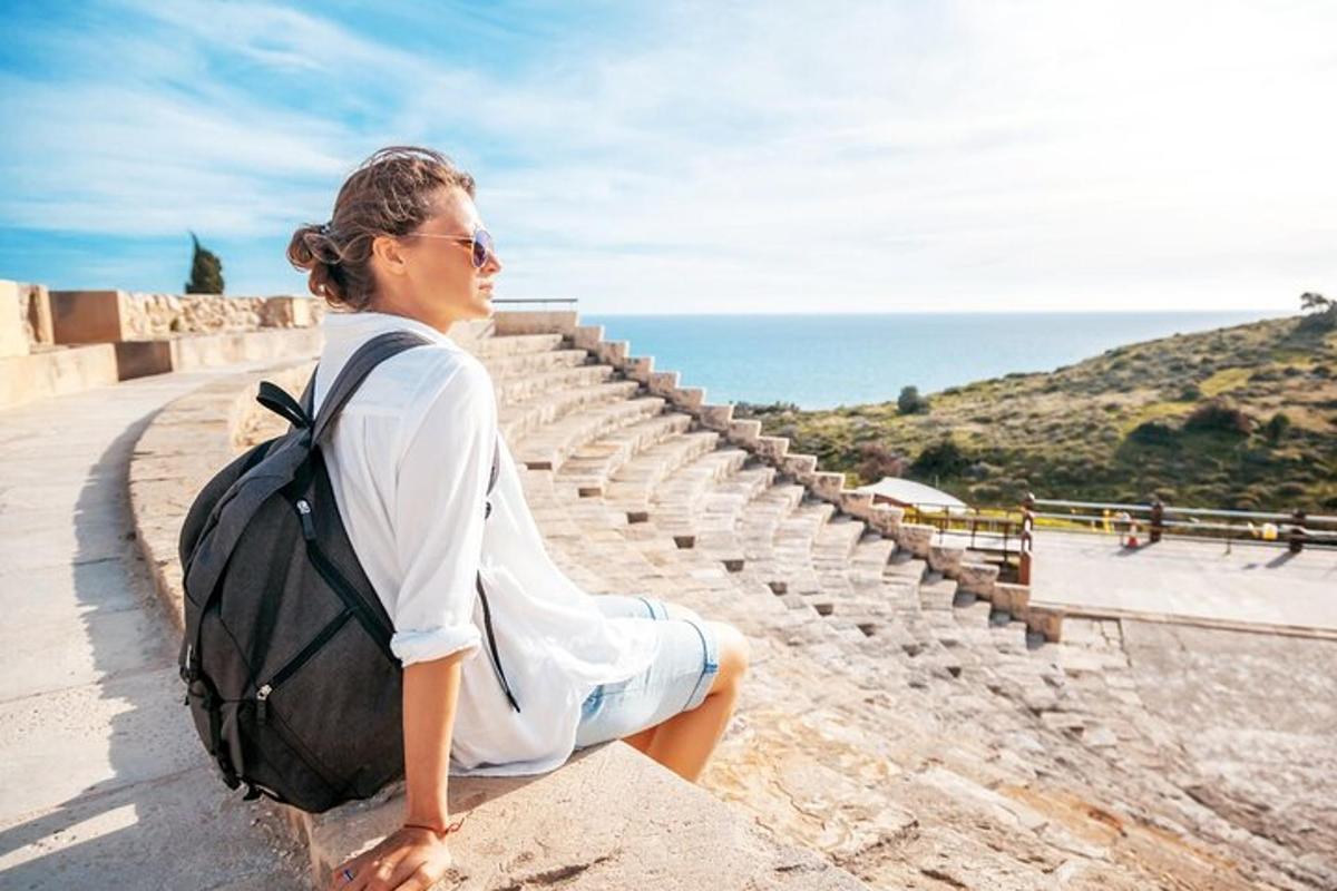 a woman sitting on a ledge with a backpack