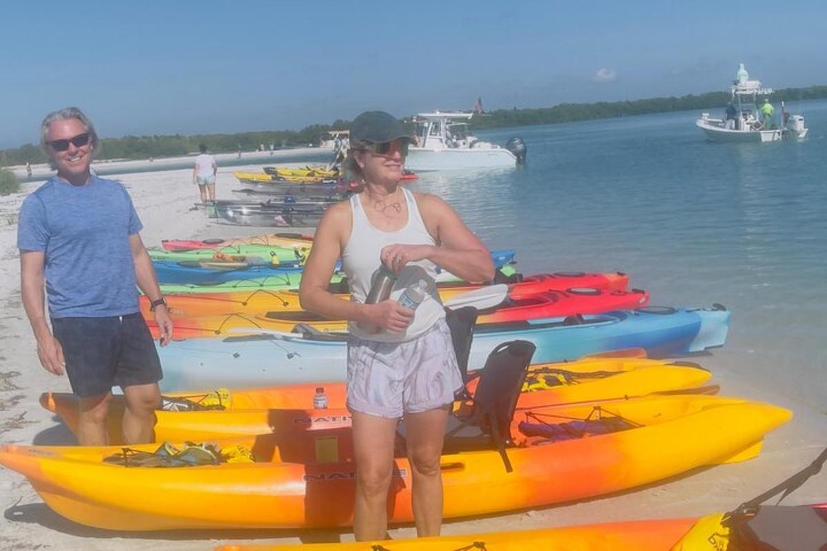 một người phụ nữ đứng trên bãi biển bên cạnh một nhóm thuyền kayak