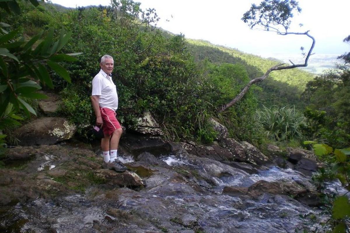 seorang lelaki berdiri di atas batu di sebelah sungai