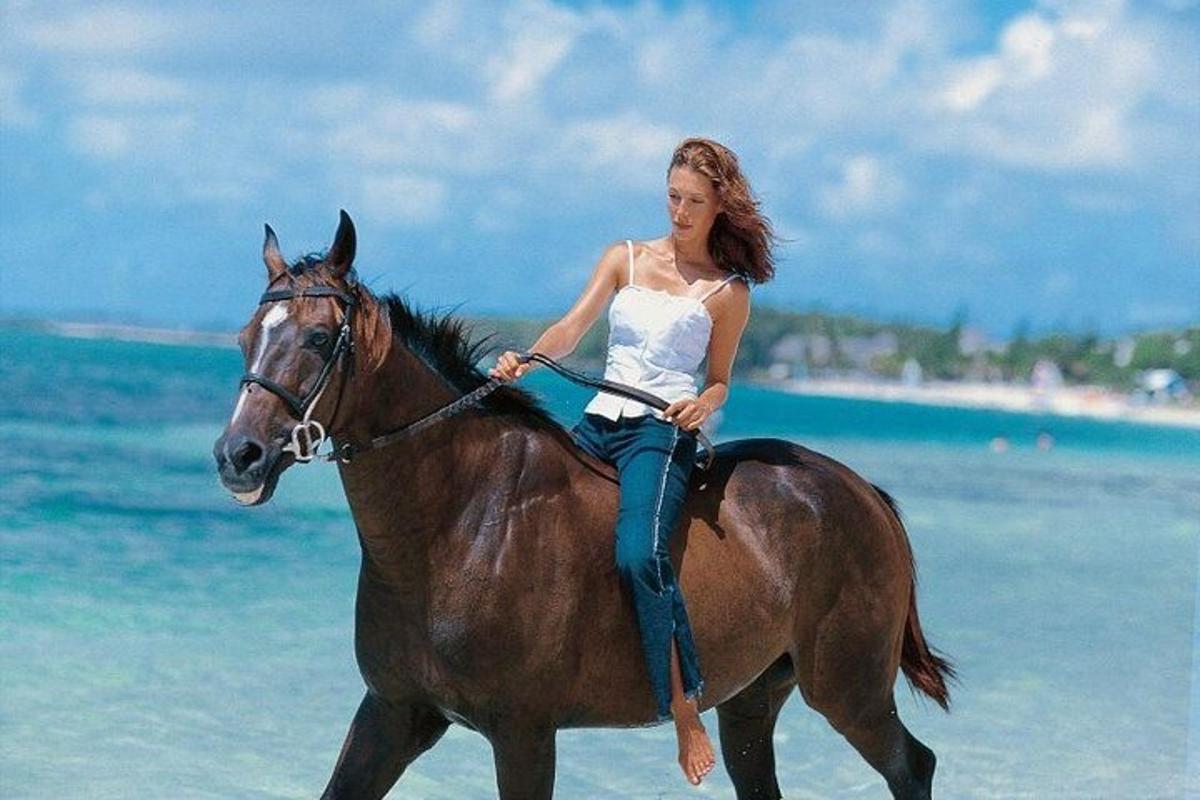 žena jaše konja na plaži