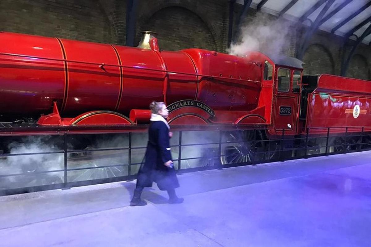Un hombre pasa junto a un tren rojo en un museo.