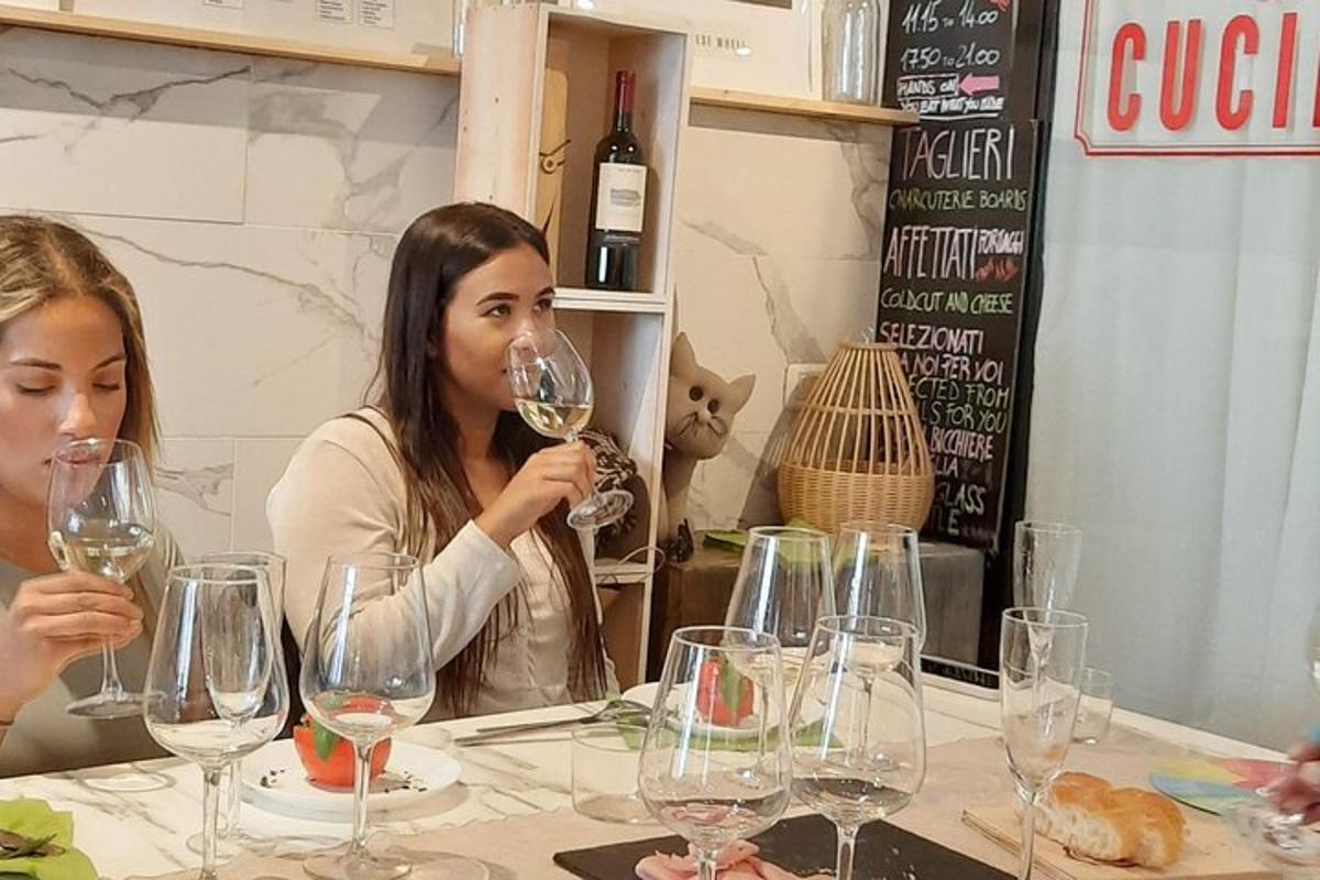 duas mulheres sentadas à mesa com taças de vinho