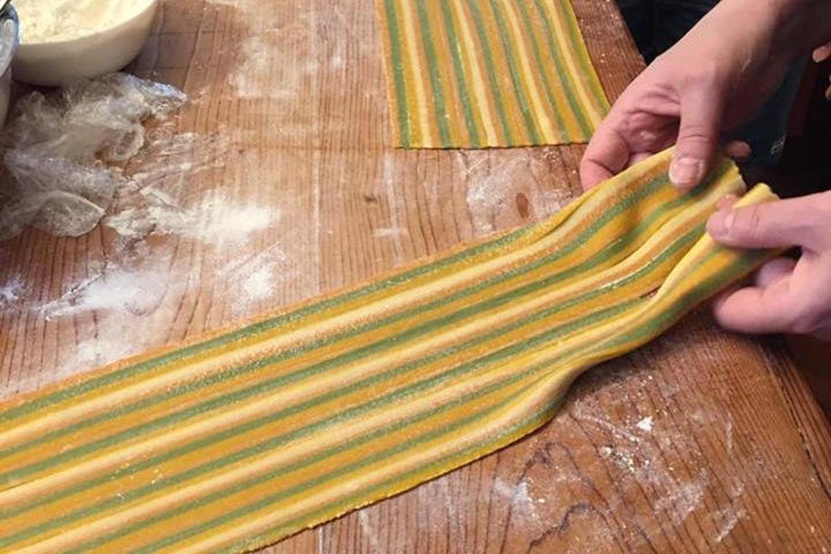 una persona che tiene in mano un lungo pezzo di cibo su un tagliere