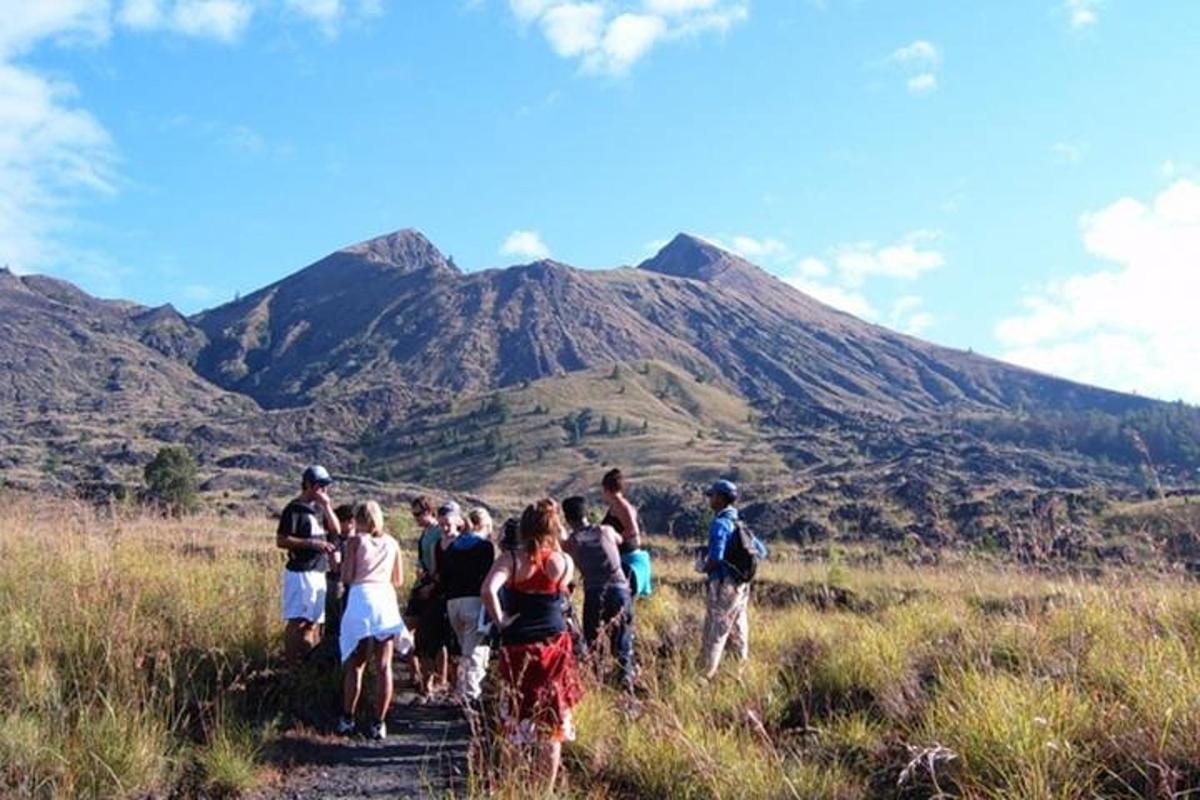 a group of people walking on a trail in front of a mountain