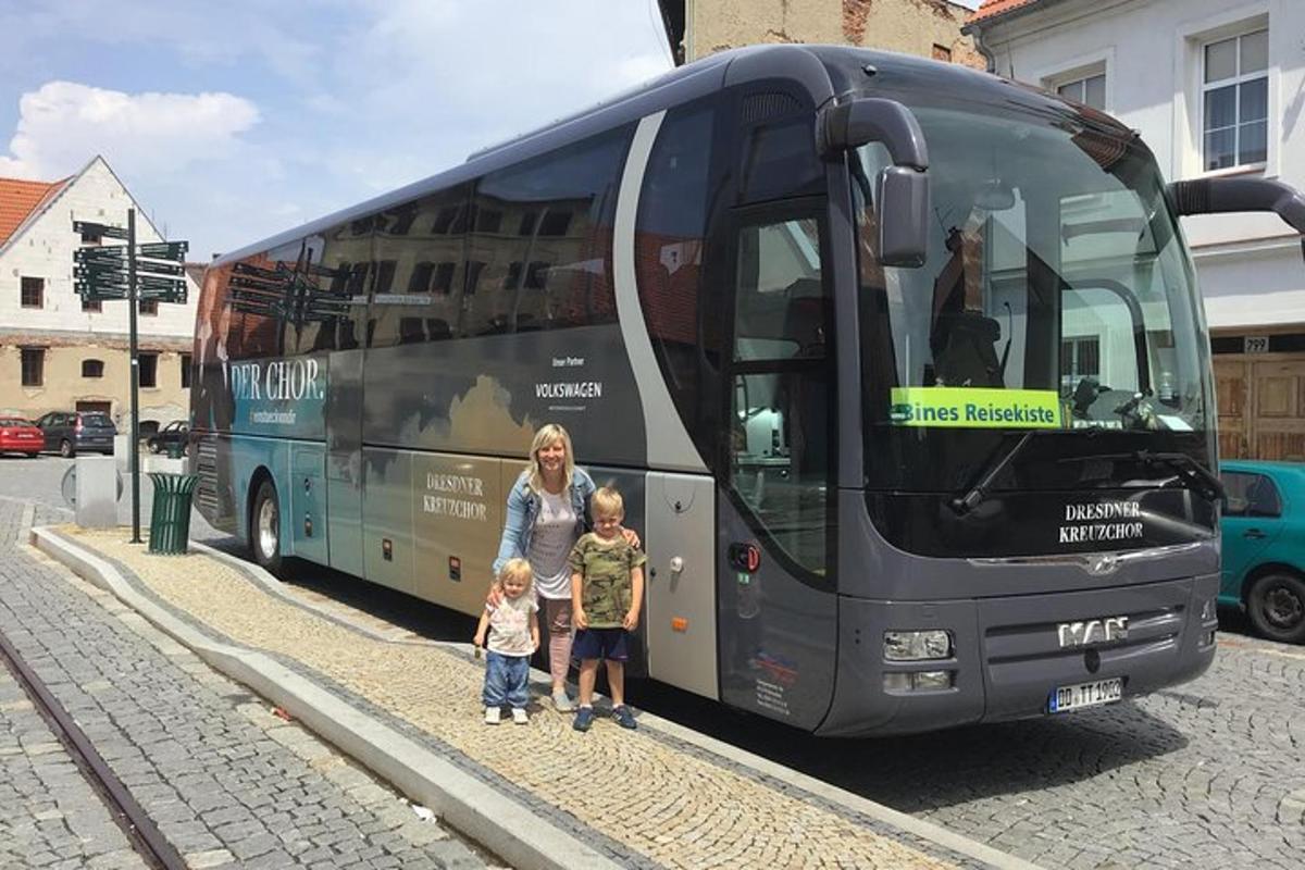 una dona i dos nens drets davant d'un autobús