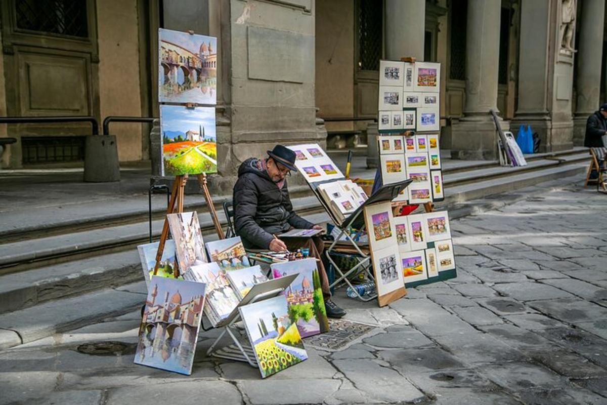 muž sedící na ulici s hromadou obrázků
