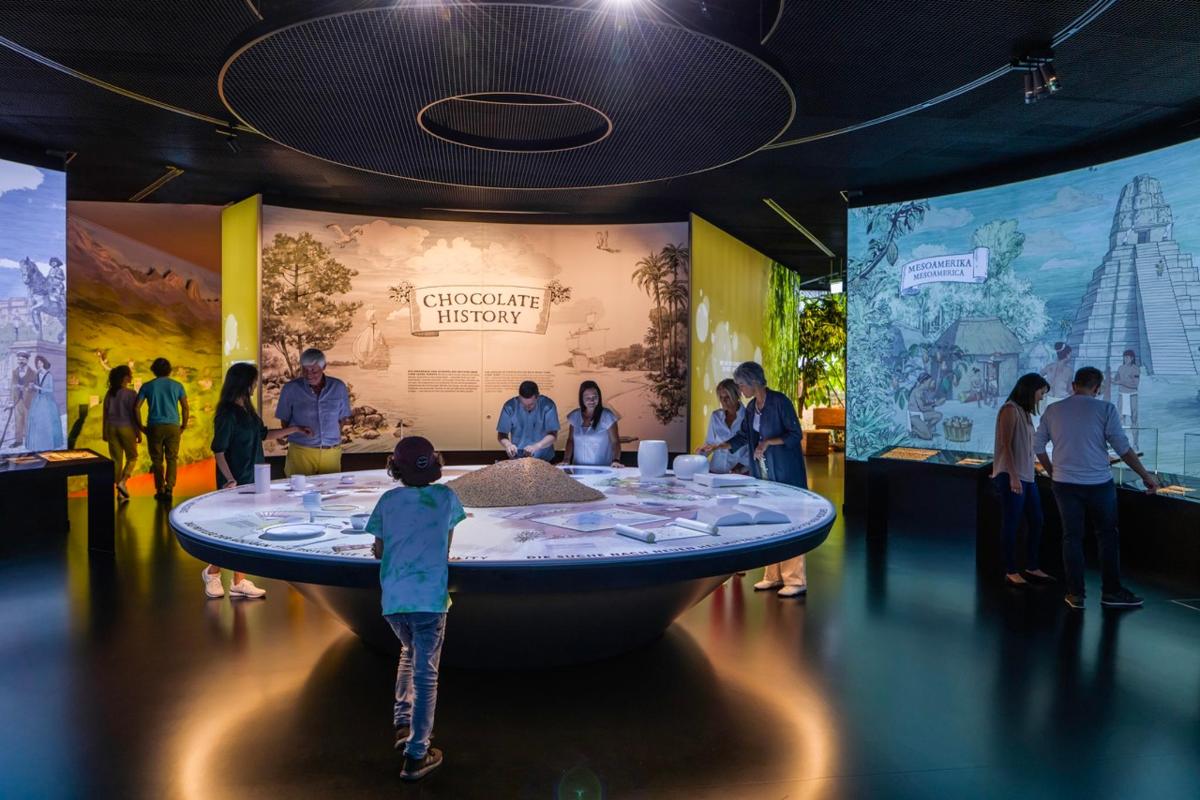 a group of people standing around a round table in a museum