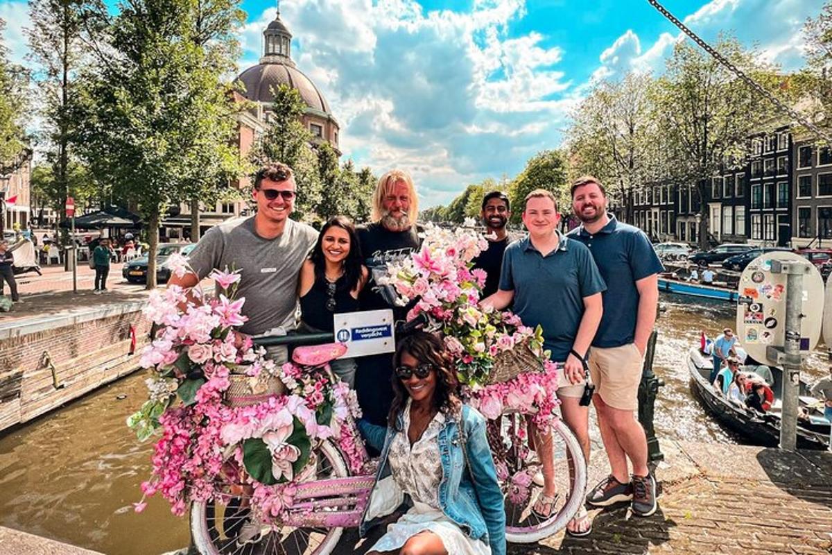 en gruppe mennesker poserer med en sykkel dekket av blomster