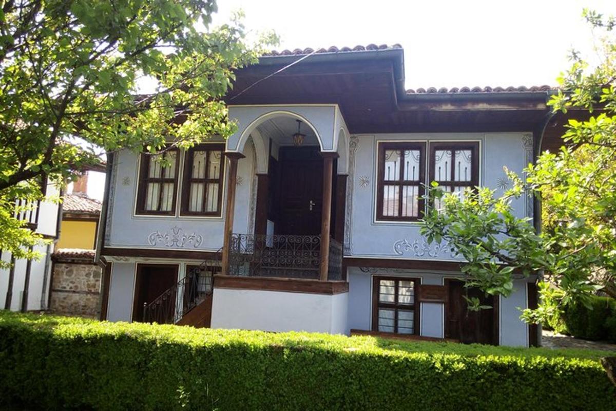 bela hiša s črnimi vrati in živo mejo