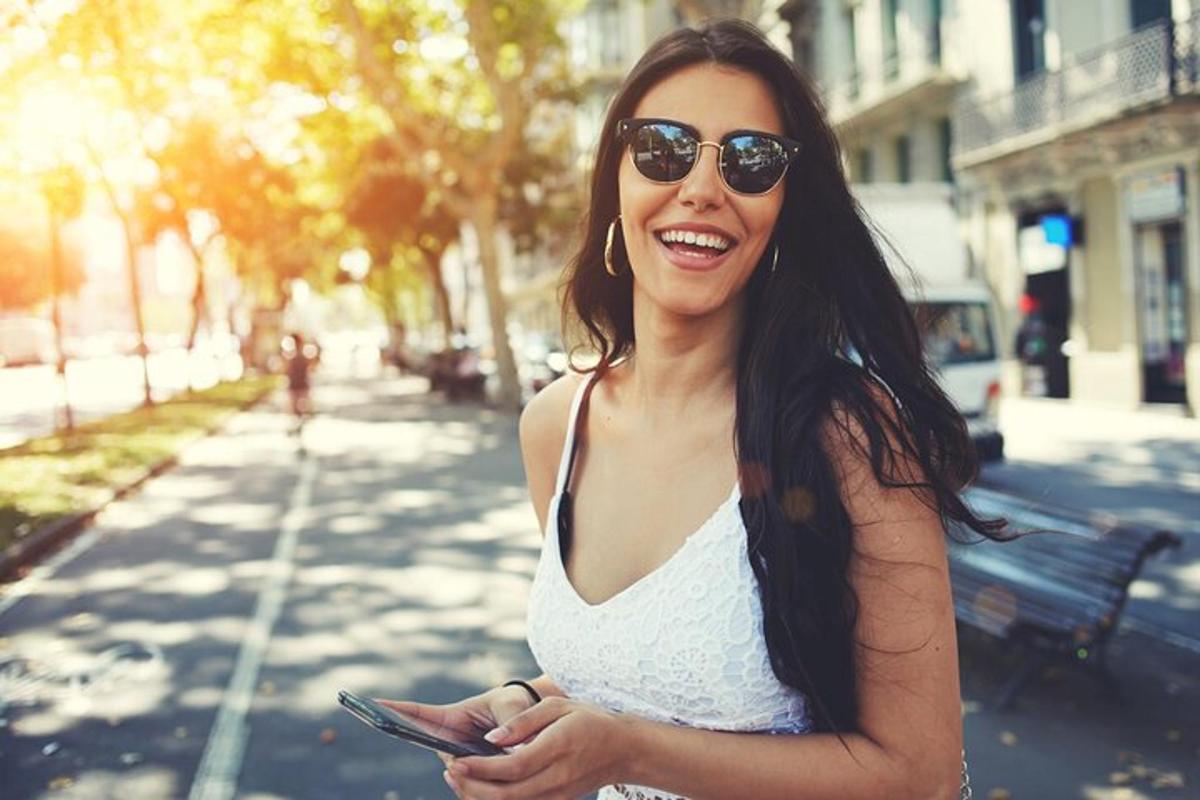 žena se slunečními brýlemi drží mobilní telefon