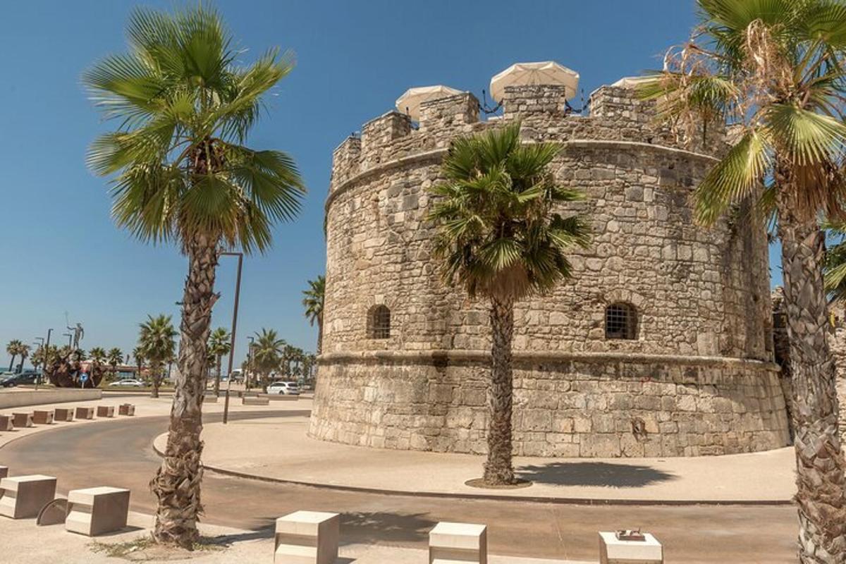 ένα πέτρινο κτίριο με φοίνικες μπροστά του