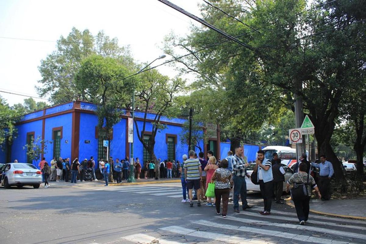a group of people walking down a street with a blue building