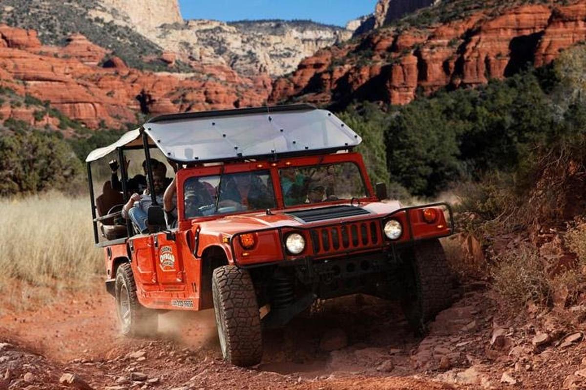 una jeep arancione che percorre una strada sterrata